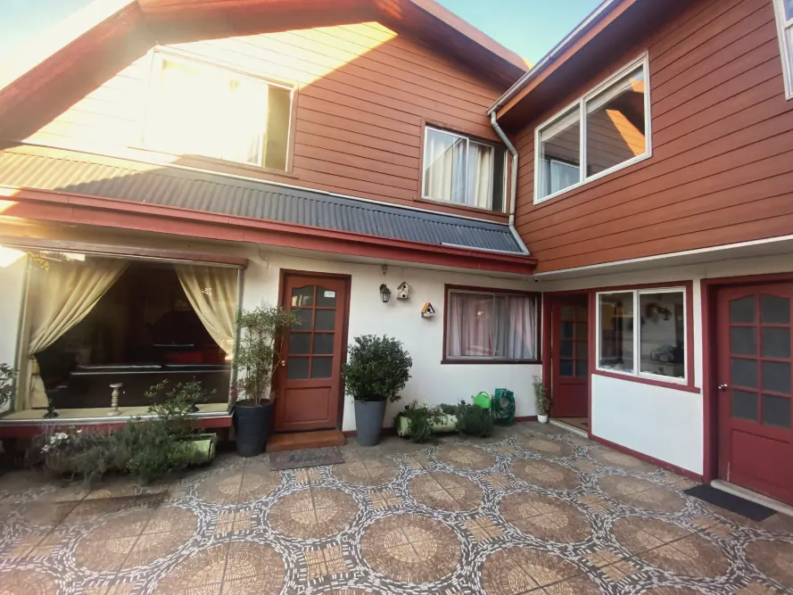 Casa para empresas con fachada de madera roja y patio de baldosas
