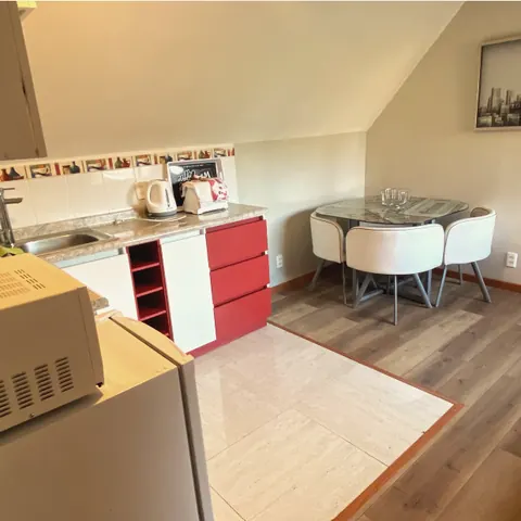 Cocina del departamento con microondas, refrigerador y mesa para dos