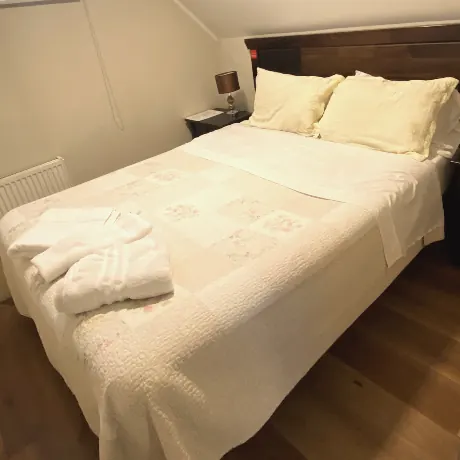 Dormitorio del departamento con cama de dos plazas bajo el techo inclinado