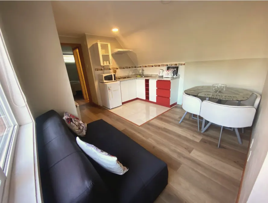 Living con sofá, comedor y cocina equipada de uno de los departamentos