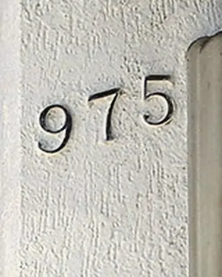Número 975 en el muro blanco de la entrada del hostal