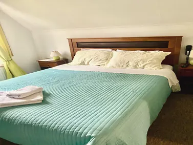 Ambiente de la cuádruple con cama matrimonial y cubrecama verde agua