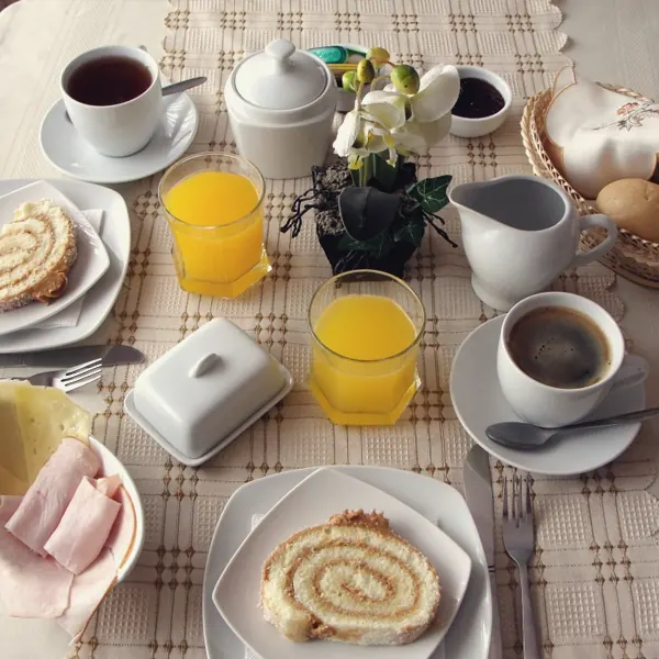 Desayuno servido con jugo, café, arrollado, jamón, queso y pan