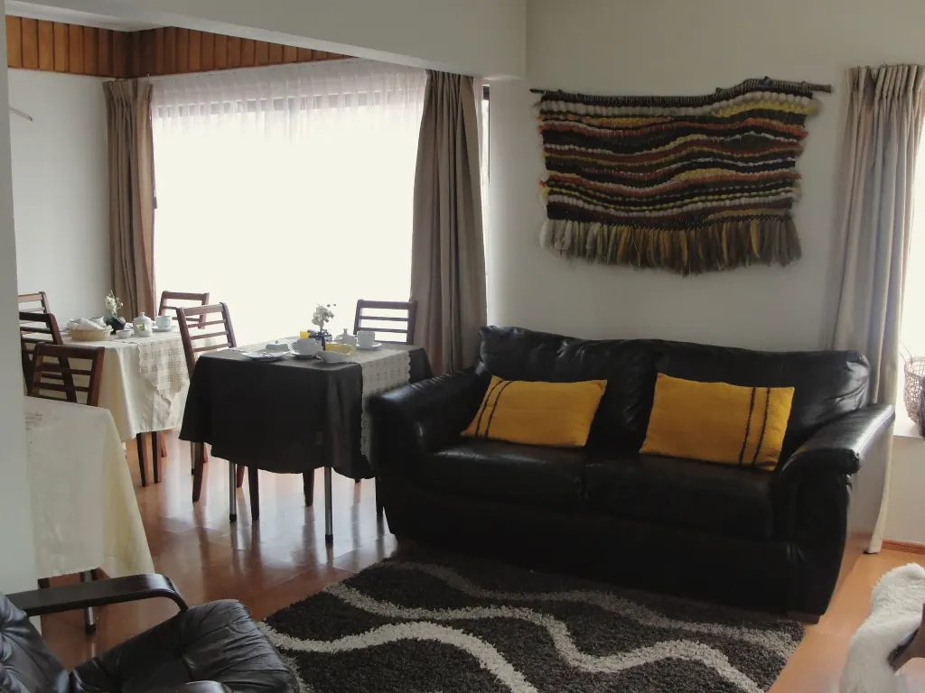 Sala de estar del hostal con sillones de cuero y un telar de lana en la pared