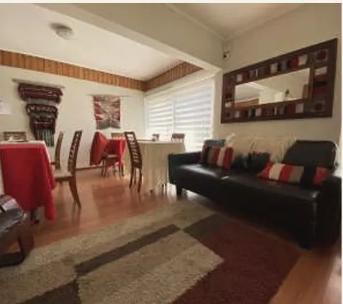 Sala de estar con sillón de cuero negro, cojines rojos y espejo de marco tejido