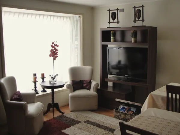 Sala de estar con dos sillones blancos y una orquídea junto a la ventana